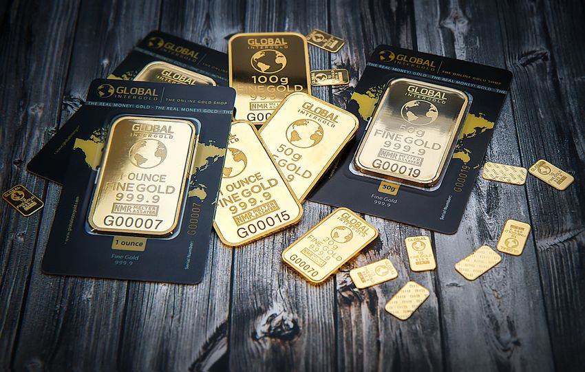 A collection of fine gold bars displayed on a textured wooden surface.