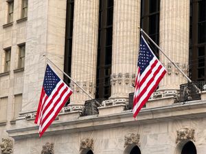 American flags displayed prominently on a historic Wall Street building in New York City.