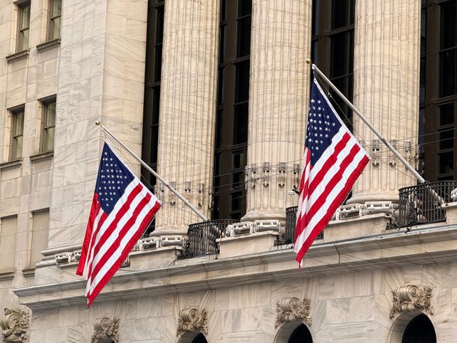 American flags displayed prominently on a historic Wall Street building in New York City.