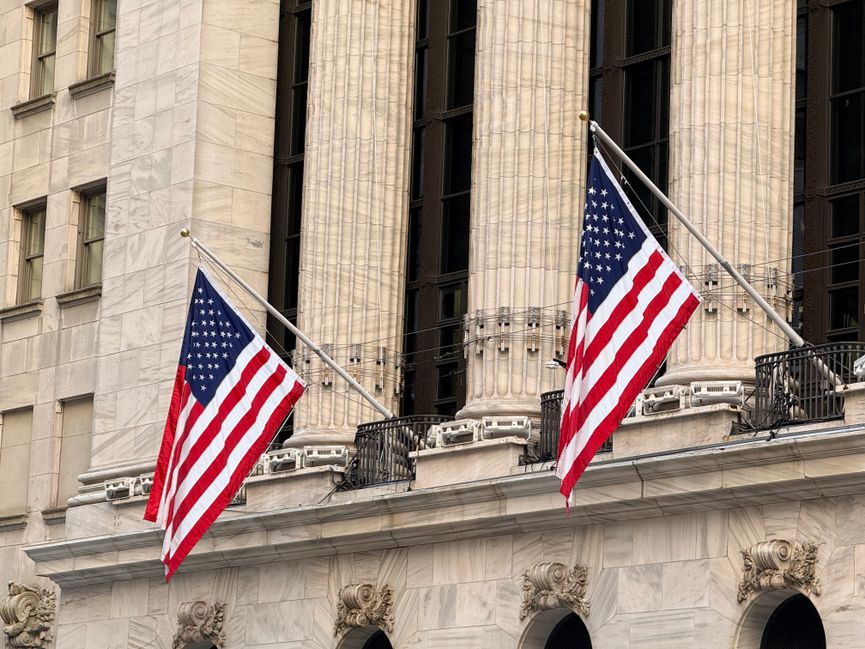 American flags displayed prominently on a historic Wall Street building in New York City.