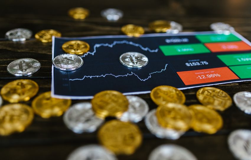 Bitcoin and altcoins on table with digital trading chart indicating market trends and investment details.