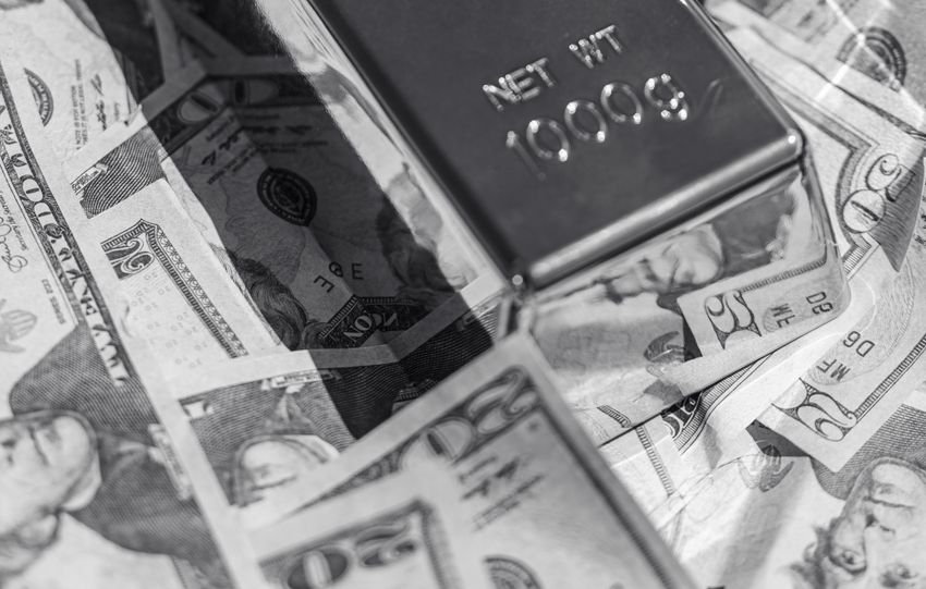 Black and white image of gold bars placed on scattered US dollar bills, symbolizing wealth.