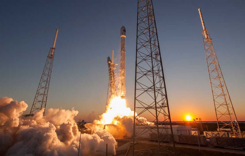 Low angle of modern rocket taking off into cloudless sky during beautiful sunset over space factory
