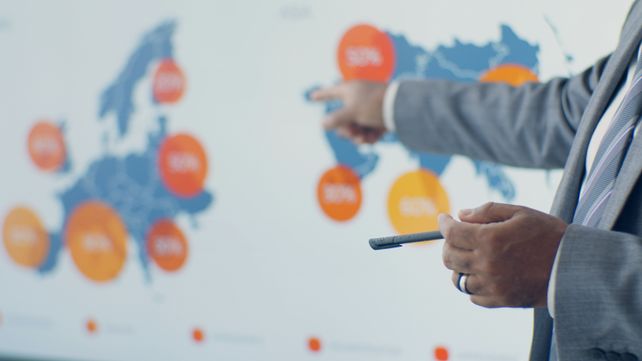Professional presenting detailed analytics on European map during office meeting.