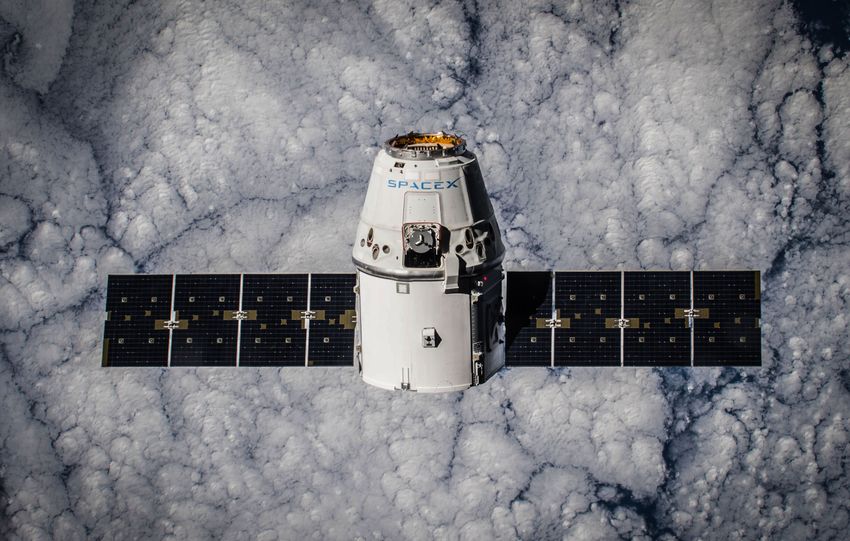 SpaceX Dragon spacecraft in orbit, highlighting advanced space technology with cloud backdrop.