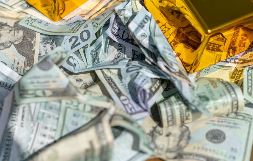 Two gold bars rest on a pile of US dollar bills, symbolizing wealth and prosperity.