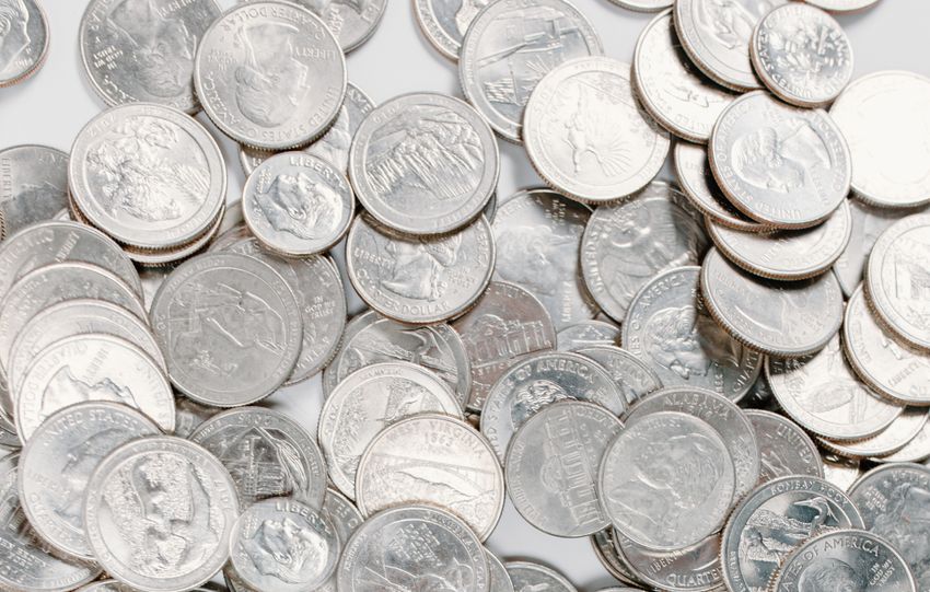 A large collection of silver coins scattered randomly on a white background.