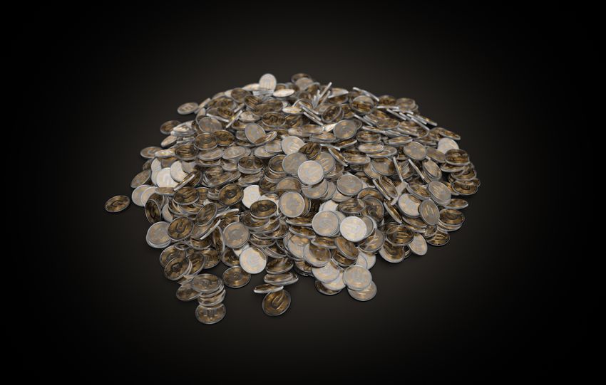 A large pile of assorted coins on a dark black background, symbolizing wealth and finance.