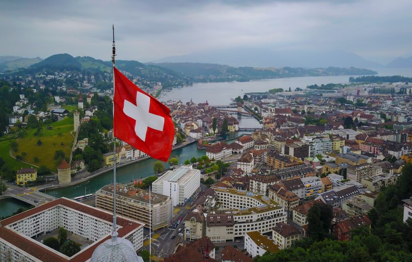 A stunning aerial view of Lucerne, Switzerland with a Swiss flag and scenic lake backdrop.