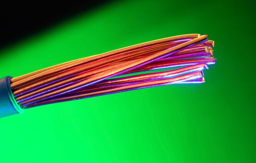 Close-up of colorful copper electrical wires against a vibrant green backdrop, showcasing vivid contrasts and textures.