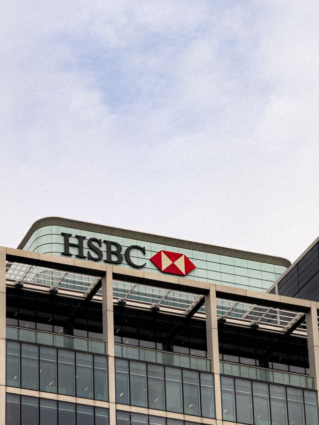 Contemporary architecture of HSBC's headquarters with glass facade under a clear sky.