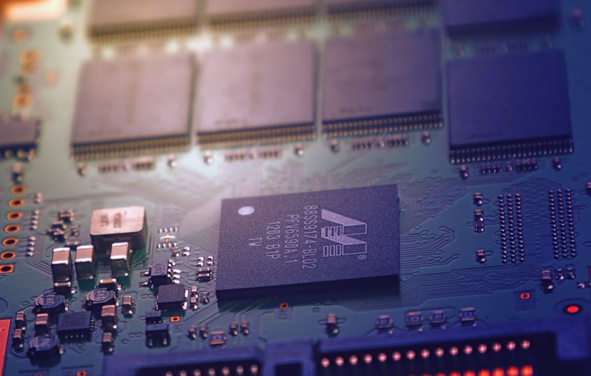 Detailed image of an electronic circuit board showing microchips and intricate wiring in a modern technological setting.