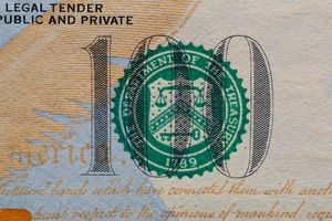 Detailed view of the US 100 dollar bill showing the Treasury seal and printed text.