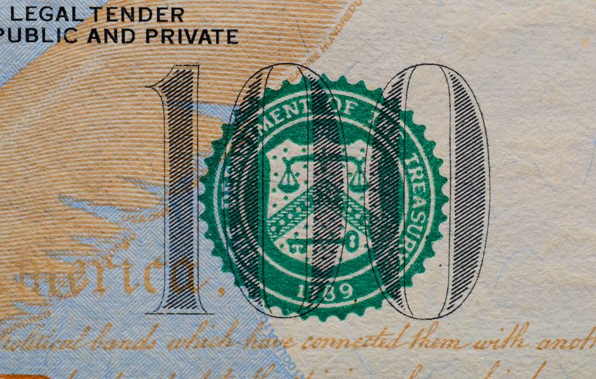 Detailed view of the US 100 dollar bill showing the Treasury seal and printed text.