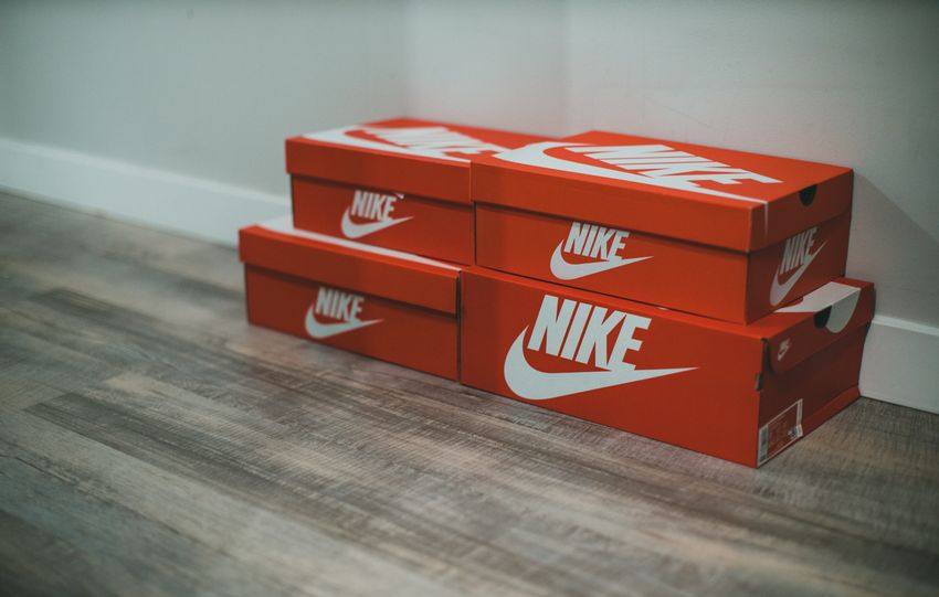 Red Nike shoe boxes stacked neatly on a wooden floor indoors.