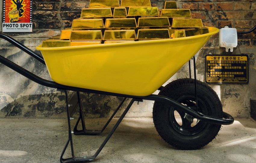 Vibrant gold bar display in a wheelbarrow on a Beijing street, capturing the urban charm.
