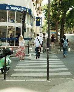 A street scene in Paris with people crossing near La Compagnie Bllu on a warm day.