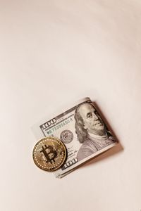 Bitcoin coin placed over US dollar note symbolizes digital vs traditional currency.