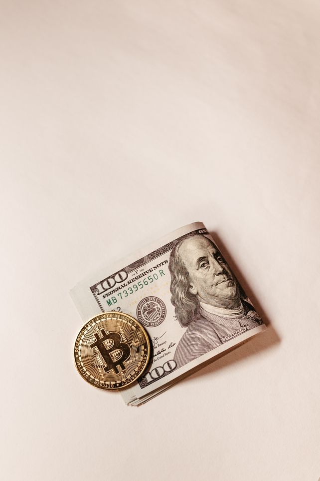 Bitcoin coin placed over US dollar note symbolizes digital vs traditional currency.