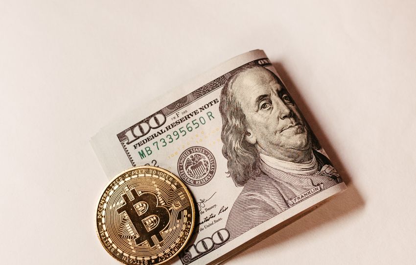 Bitcoin coin placed over US dollar note symbolizes digital vs traditional currency.