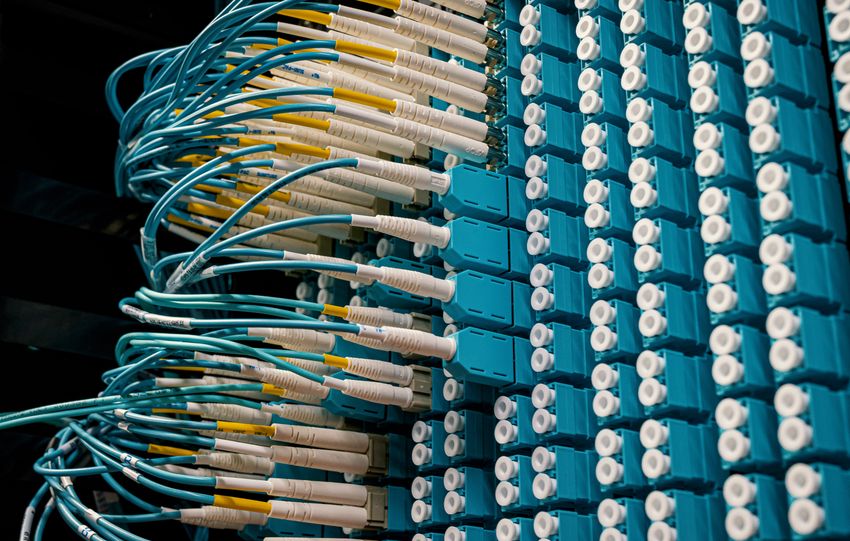 Detailed view of fiber optic patch cables connecting to a blue patch panel in a data center.