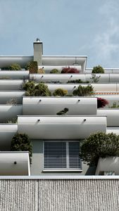 Vertical shot of a modern apartment building with lush terrace gardens and clear sky.
