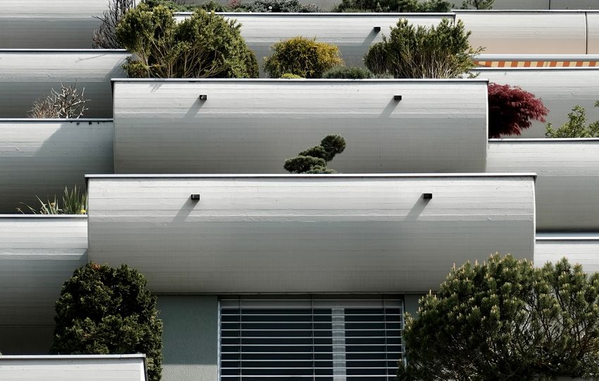 Vertical shot of a modern apartment building with lush terrace gardens and clear sky.