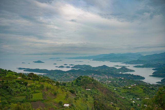 A breathtaking view of a lake with scattered islands and lush green landscapes under a cloudy sky.