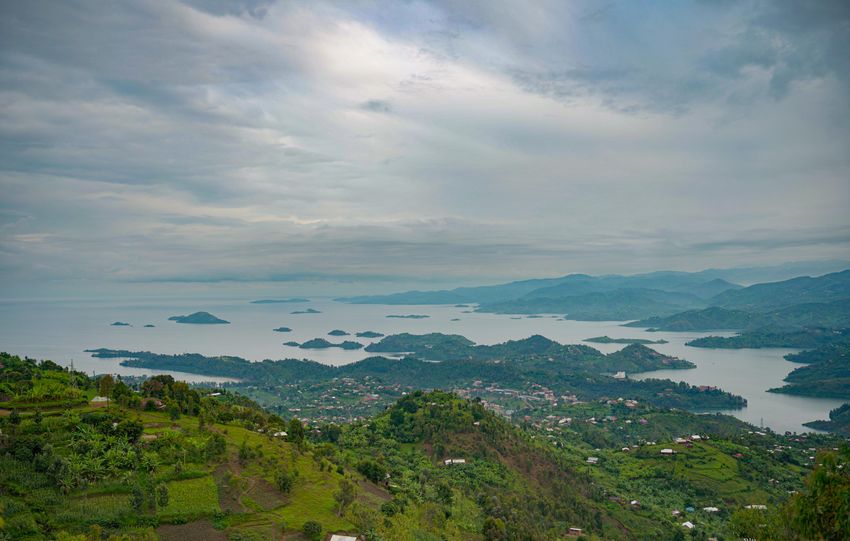 A breathtaking view of a lake with scattered islands and lush green landscapes under a cloudy sky.