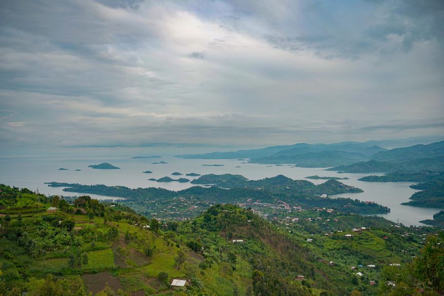 A breathtaking view of a lake with scattered islands and lush green landscapes under a cloudy sky.