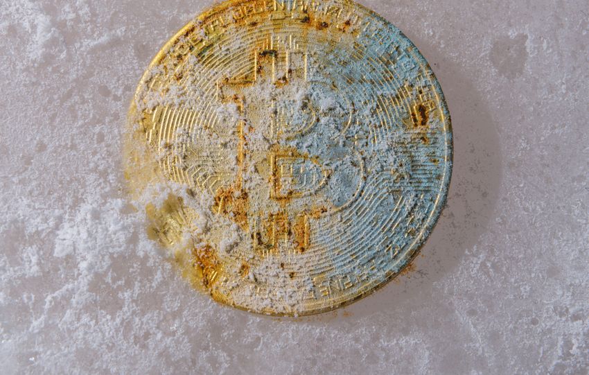 A gold Bitcoin coin partially covered in ice, symbolizing cryptocurrency's unpredictable market conditions.