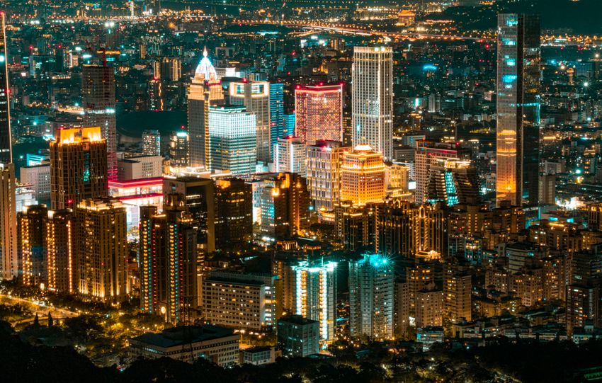 A stunning aerial view of a vibrant cityscape at night, showcasing modern skyscrapers illuminated against the night sky.