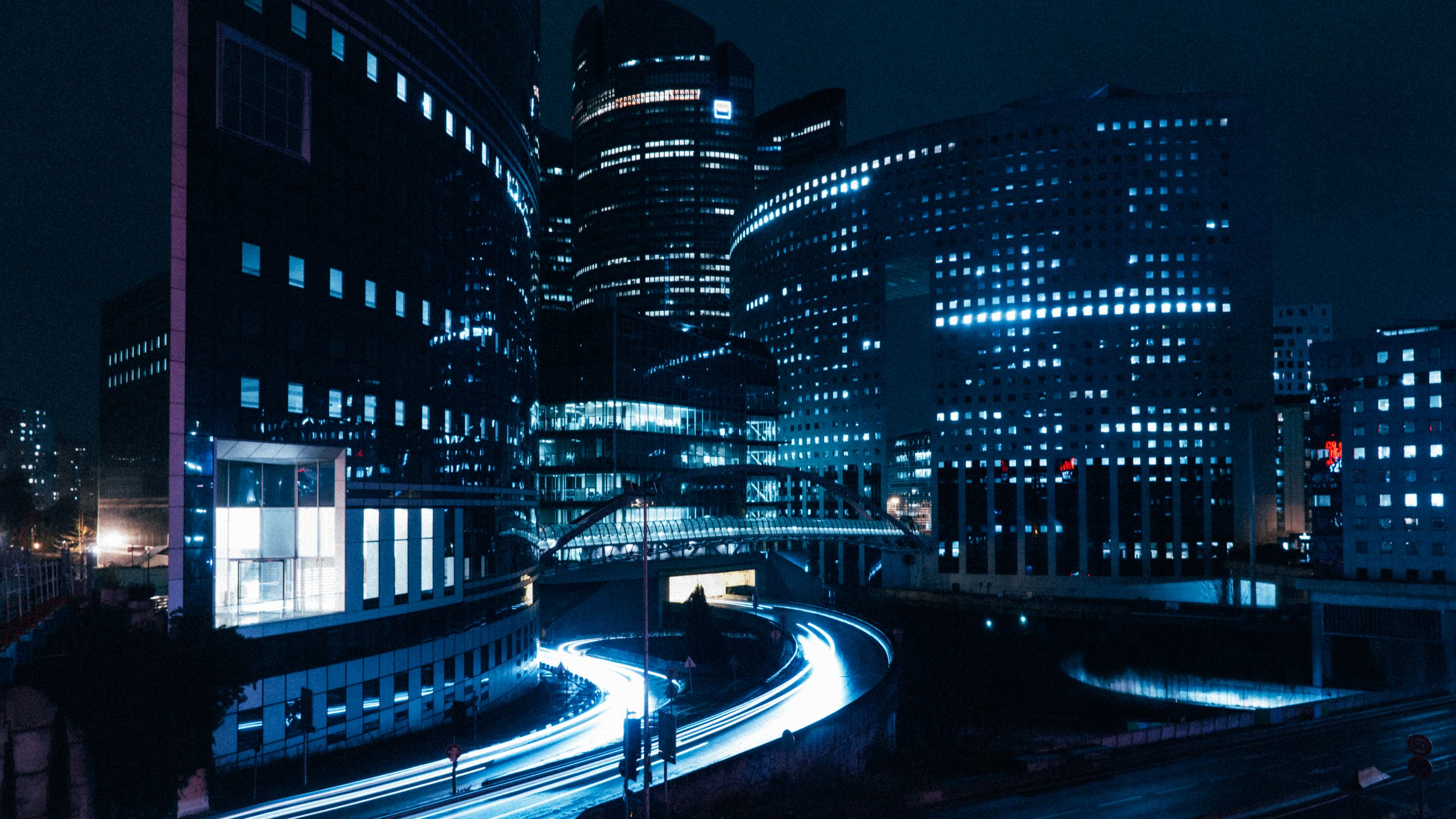 A stunning view of modern city buildings illuminated at night with dynamic light trails.