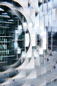 Abstract image capturing geometric reflections on a modern urban building with people walking nearby.