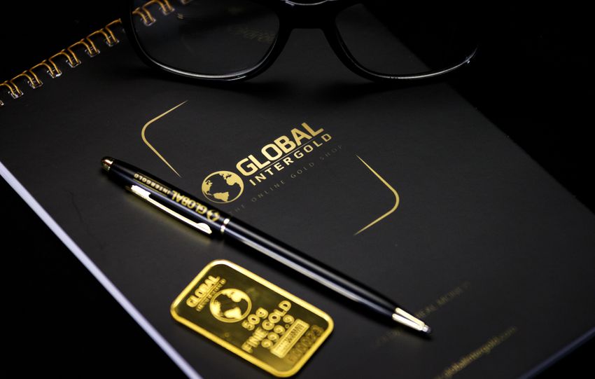 An elegant setup with a notebook, pen, and gold bar, embodying luxury and style.