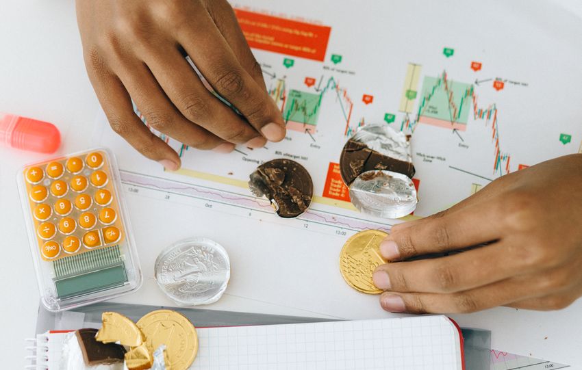 Analyzing financial charts with a calculator and chocolate coins.
