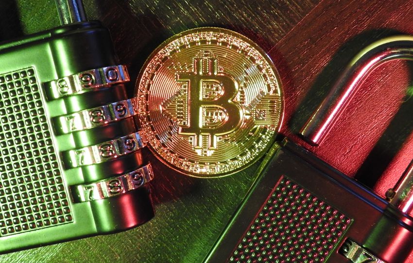 Bitcoin coin with combination padlocks on a wooden surface, symbolizing cryptocurrency security and encryption.