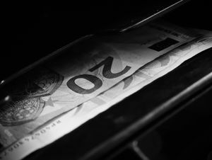 Black and white image highlighting a 20 euro bill in a cash register, capturing financial concepts.