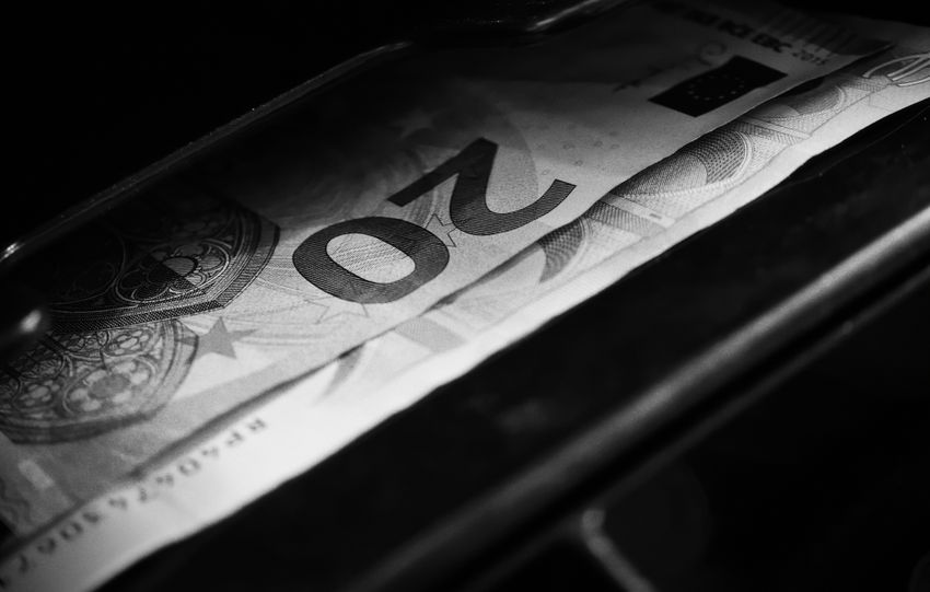 Black and white image highlighting a 20 euro bill in a cash register, capturing financial concepts.