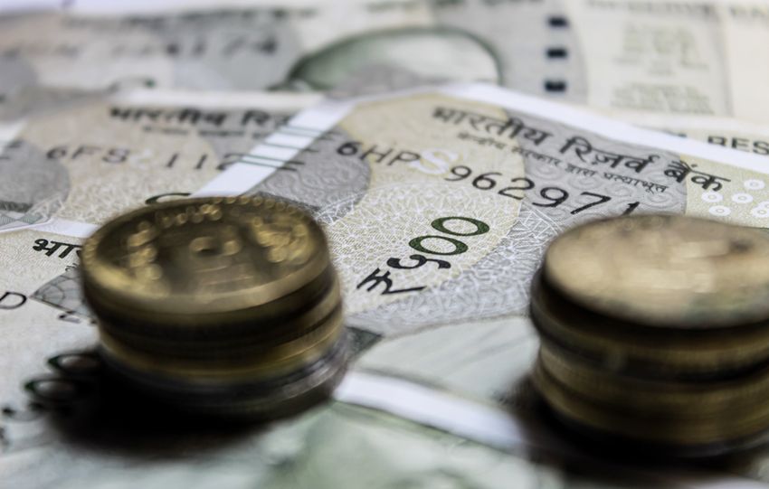 Detailed close-up of Indian rupee coins on top of banknotes, representing finance.