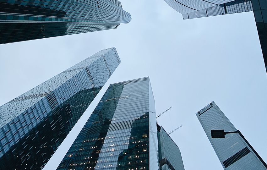 From below of modern skyscrapers with glass mirrored windows located in business district against blue cloudy sky