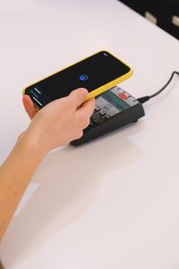Person using a smartphone for contactless payment on a terminal. Simplifies transactions.