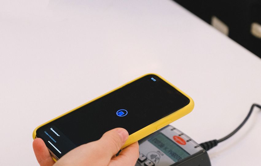 Person using a smartphone for contactless payment on a terminal. Simplifies transactions.