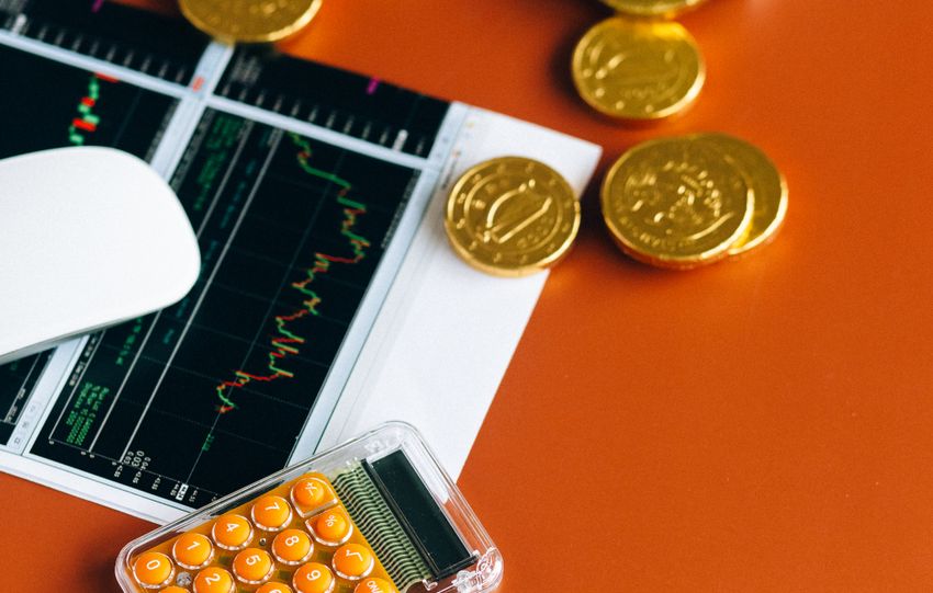 Stock market and financial analysis setup with calculator, graphs, and gold coins.