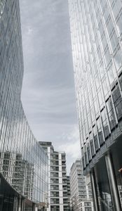 Vertical view of modern skyscrapers in Warsaw with glass facades reflecting the sky.