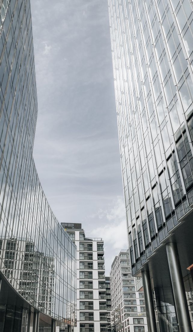 Vertical view of modern skyscrapers in Warsaw with glass facades reflecting the sky.