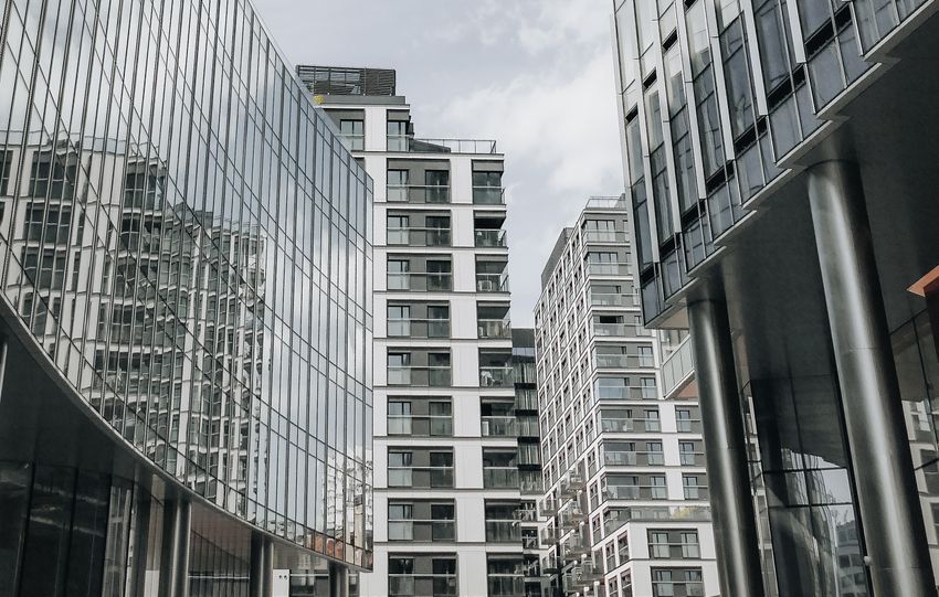 Vertical view of modern skyscrapers in Warsaw with glass facades reflecting the sky.