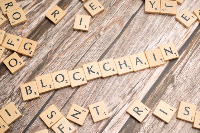 Wooden letter tiles form the word 'blockchain' arranged on a rustic wood background.