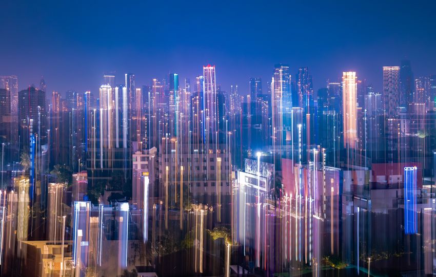A dynamic capture of Jakarta's skyline at night with vibrant neon light streaks and city lights.