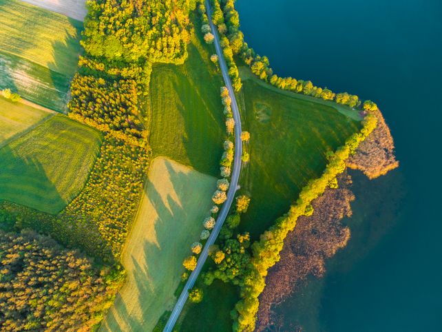 A stunning aerial view of a lush green countryside with winding roads and shimmering blue water.